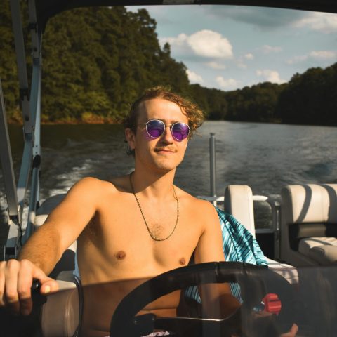 a person in sunglasses sitting in front of a mirror posing for the camera